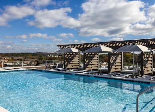 A swimming pool with a metal railing and umbrellas at 2020 Providence in Huntsville, AL