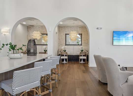 A modern living room with a white sofa and a TV on the wall.