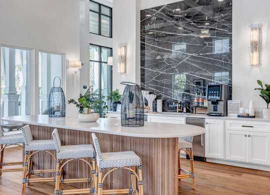 A kitchen with a marble backsplash and a bar area with chairs.
