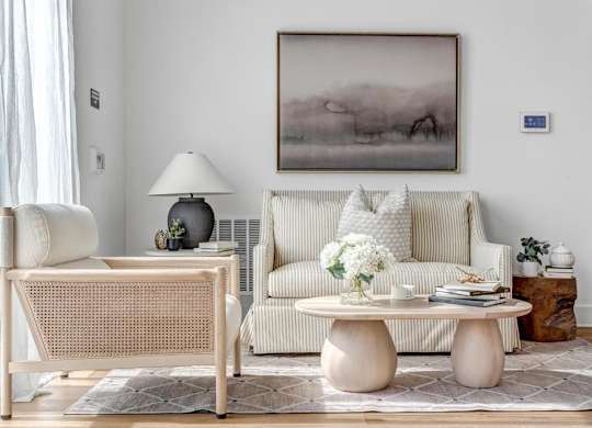 A living room with a couch, a table, and a painting on the wall.