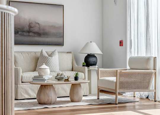 A living room with a sofa, a chair, and a table with decorative items.