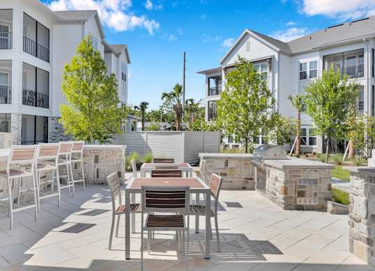 A patio with a table and chairs is surrounded by apartment buildings.