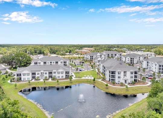 A large building complex with a pond in front and a lake in the background.