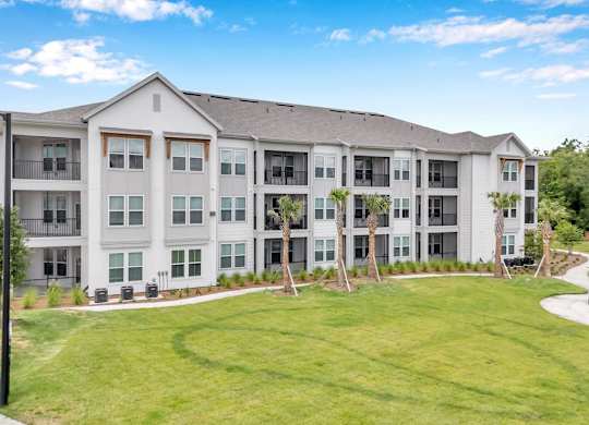 A large white apartment building with a green lawn in front.