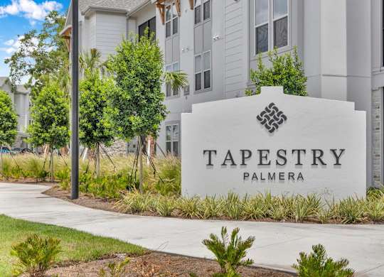 A sign for Tapestry Palmera in front of a building.