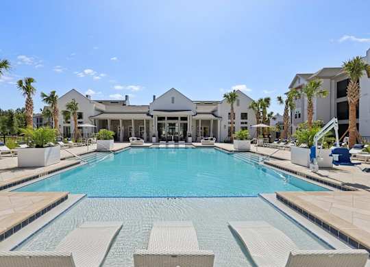A large swimming pool surrounded by lounge chairs and palm trees.