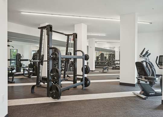 A gym with a weightlifting machine and a rowing machine at Tapestry University Park in Sarasota, FL