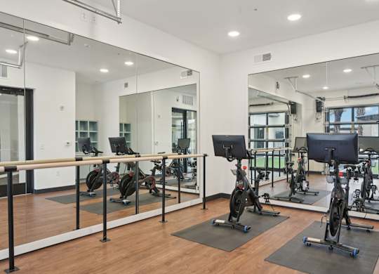 A gym with a mirrored wall and exercise bikes at Tapestry University Park in Sarasota, FL
