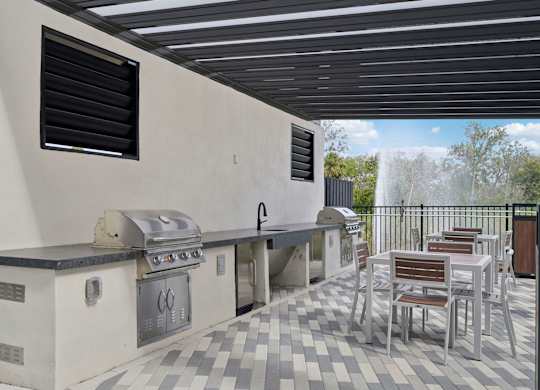 Outdoor kitchen with tables and chairs and a tv at Tapestry University Park Apartments in Sarasota, FL