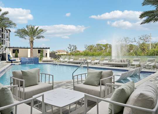 Pool with soft seating and tables at Tapestry University Park Apartments in Sarasota, FL