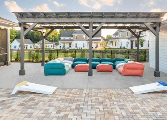 pool area with pergola, couches, and yard games at Anthem Apartments and Cottages in Huntsville, Alabama