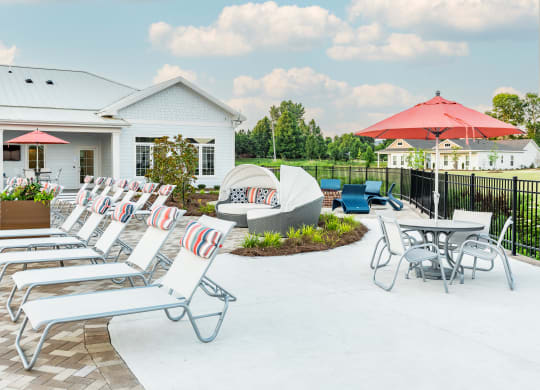 a patio with lounge chairs and umbrellas at Anthem Apartments and Cottages in Huntsville, Alabama