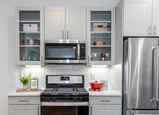 a kitchen with white cabinets, glass door fronts, and stainless steel appliances at Anthem Luxury Rentals and Apartment Homes in Huntsville, AL