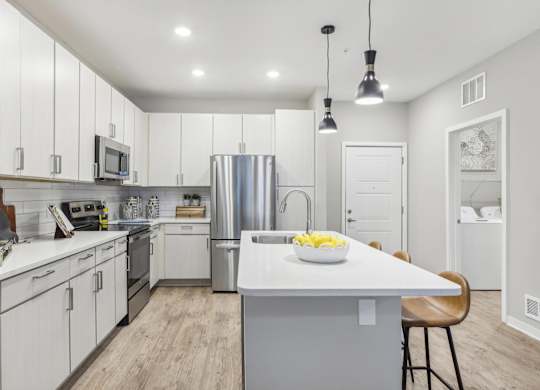 a large kitchen with white cabinets and stainless steel appliances