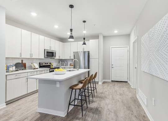 an open kitchen with white cabinets and a large island with chairs