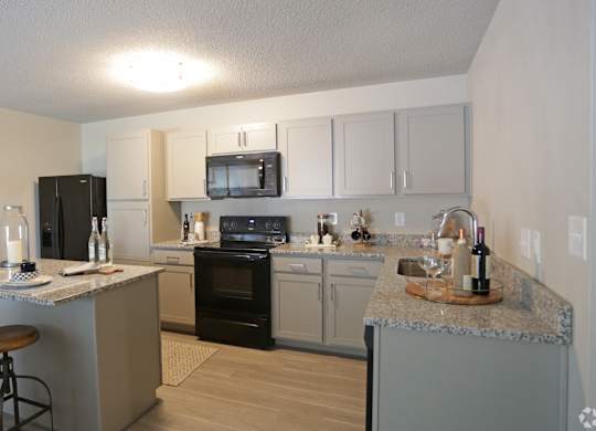 Kitchen with black appliances, wood-designed flooring, and granite countertops at Avia Apartments in Vestavia Hills, AL