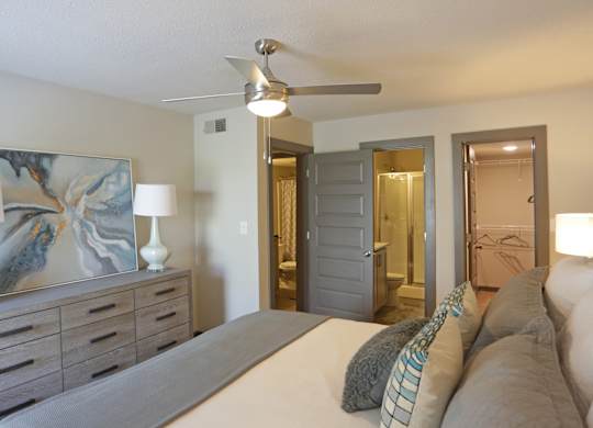 Renovated primary bedroom with ceiling fan, en-suite bathroom, and walk-in closet at Avia Apartments in Vestavia Hills, AL