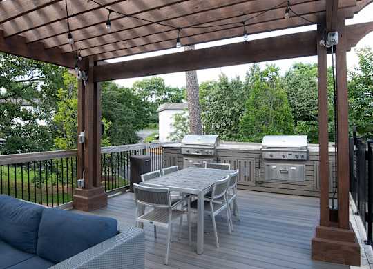 a covered deck with a table and chairs and a pergola at Avia Apartments in Vestavia Hills, AL