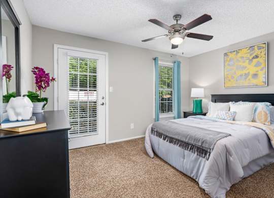 Carpeted bedroom with ceiling fan, door to patio at Summerchase at Riverchase in Hoover, Alabama
