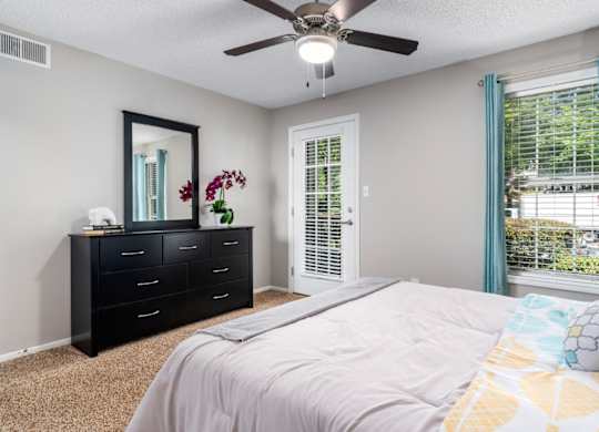 Carpeted bedroom with ceiling fan, door to patio at Summerchase at Riverchase in Hoover, Alabama