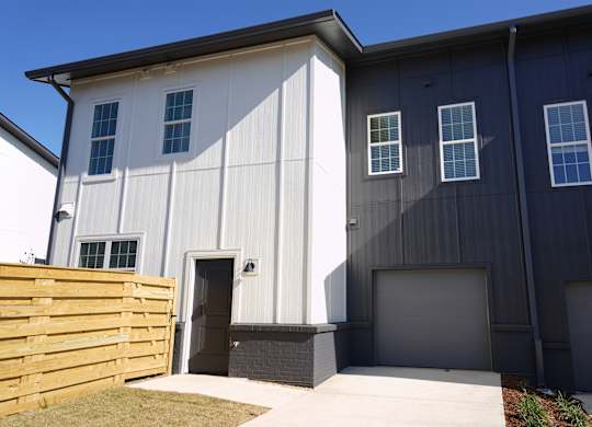 Townhouse building exterior with attached garage and fenced pet yard at West Row Lofts and Townhomes in Birmingham, AL