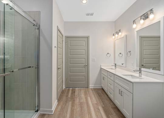 A bathroom with a walk-in shower, double sinks, and a large mirror.
