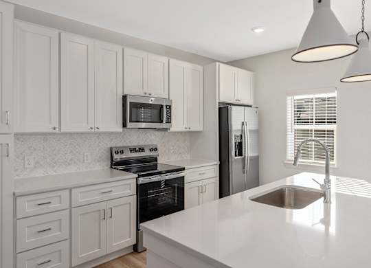 A kitchen with white cabinets and a black stove top oven.