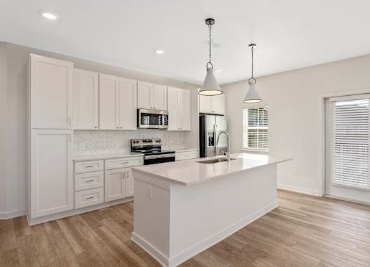 A kitchen with a white island and wooden floors.