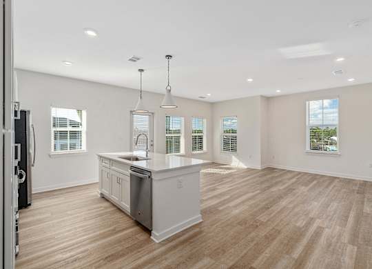 A spacious kitchen with wooden floors and white cabinetry.
