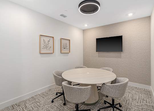 A conference room with a round table and chairs.