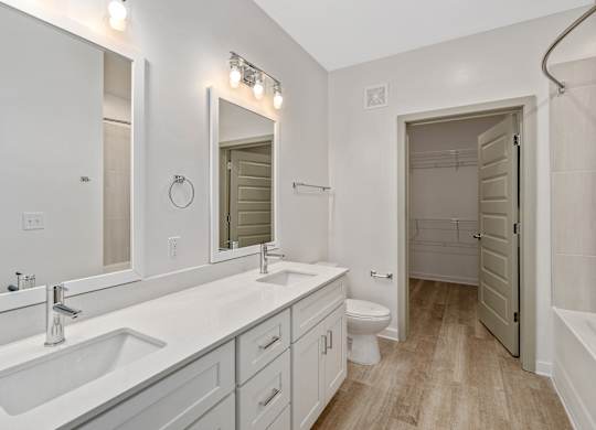 A white bathroom with a sink, toilet, and mirror.