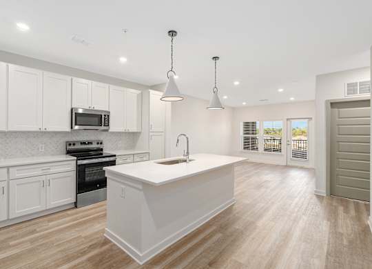 A kitchen with white cabinets and a white island.