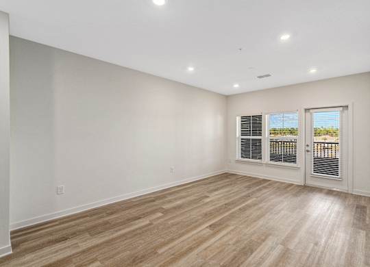 A room with wooden flooring and a sliding glass door.