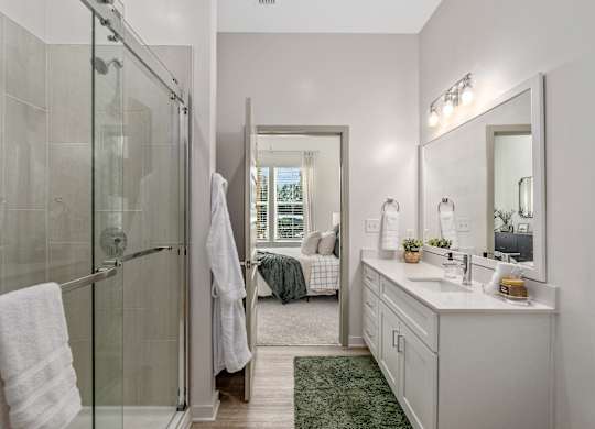 A bathroom with a glass shower stall, a white sink, and a mirror.