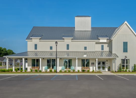 an exterior view of a white building with a parking lot at The Cottages at Foley Farms apartments in Foley, AL