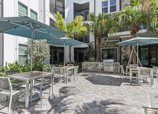 a patio with tables and umbrellas outside of a building