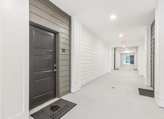 a long hallway with a black door and white walls