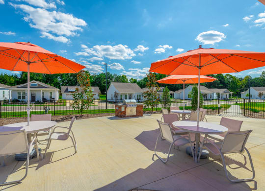 gas grilling station and tables with umbrellas at Anthem Apartments and Cottages in Huntsville, Alabama