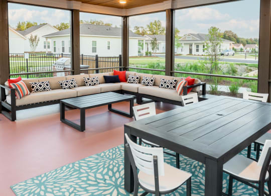 a screened patio with a couch table and chairs and large windows cottage at Anthem Apartments and Cottages in Huntsville, Alabama