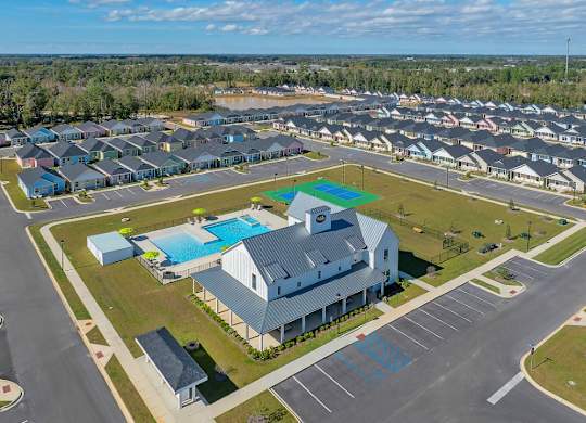 A large building with a pool in front of it is surrounded by a parking lot.