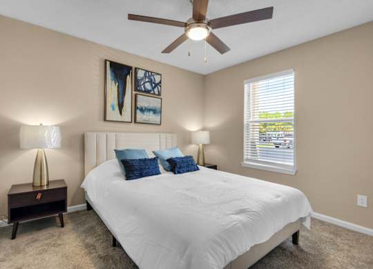 A bedroom with a ceiling fan and large window at Crystal Lake in Pensacola, Florida..
