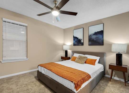 A bedroom with a bed, two nightstands, a window, and a ceiling fan at Crystal Lake in Pensacola, Florida.