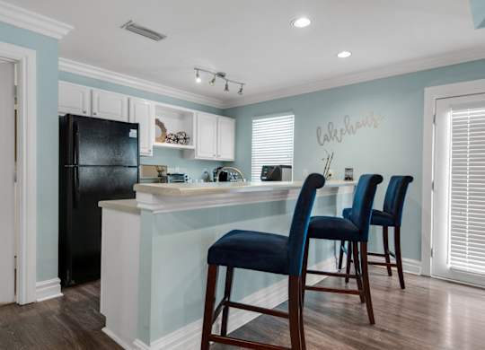 Clubhouse kitchen with a black refrigerator and white cabinets at Crystal Lake in Pensacola, Florida.