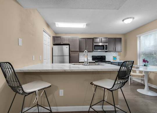 A kitchen with a white granite countertop and stainless-steel appliances at Crystal Lake in Pensacola, Florida.