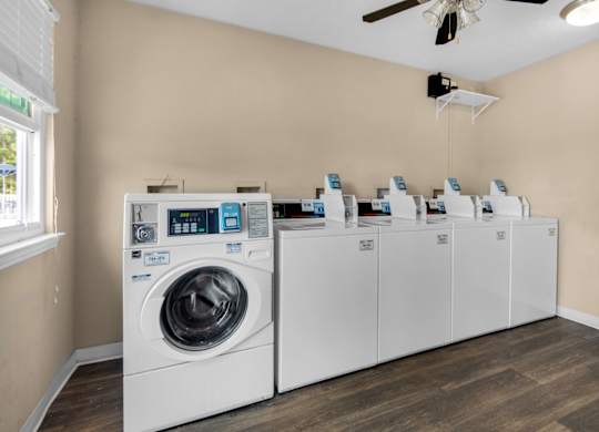 A washing machine and a row of dryers in a laundry room at Crystal Lake in Pensacola, Florida.