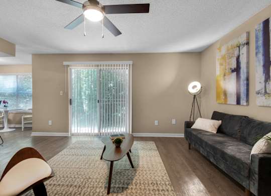A living room with a ceiling fan and a sliding door at Crystal Lake in Pensacola, Florida..