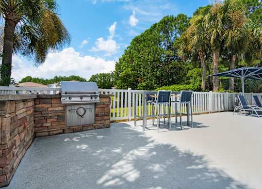 Outdoor grilling station with stone countertops and a seating area at Crystal Lake in Pensacola, Florida.