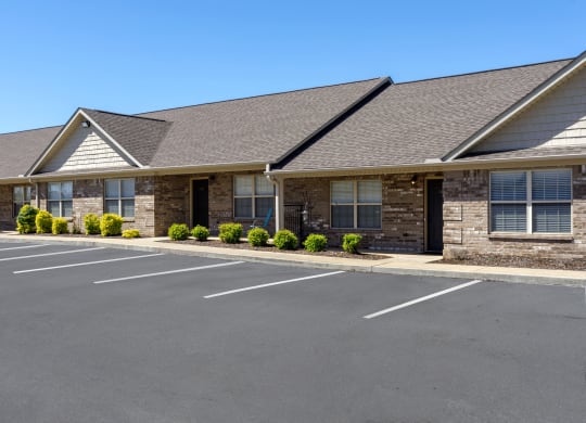 the front of a brick building with a parking lot at The Oakley at Deerfield Apartments in Florence, AL