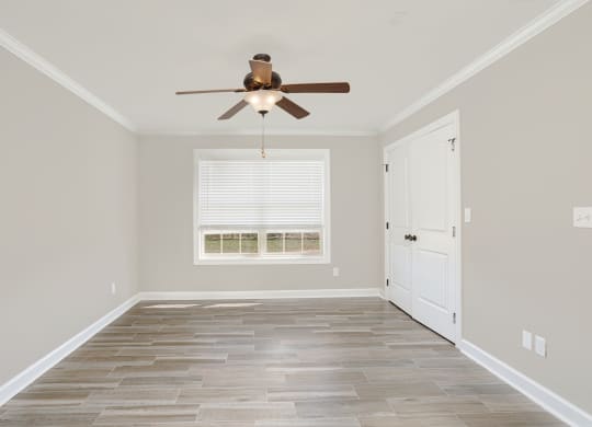 bedroom with big window and ceiling fan and wood floors at The Oakley at Deerfield Apartments in Florence, AL