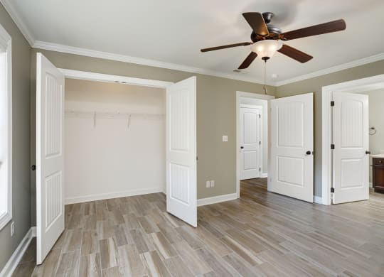 a bedroom with ensuite bathroom and ceiling fan and wood floors at The Oakley at Deerfield Apartments in Florence, AL